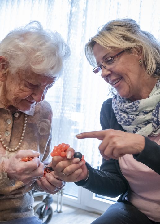 Pflegerin trainiert Handmuskulatur mit einer Dame