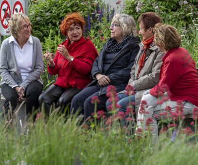 Damen sitzen zusammen auf einer Bank und unterhalten sich