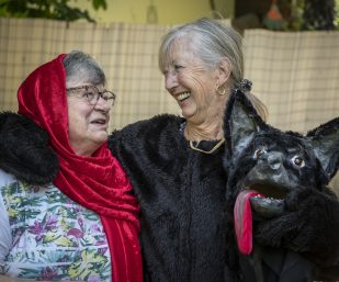 Zwei Damen lachen gemeinsam in Ihren Theaterkostümen von Rotkäppchen und der böse Wolf