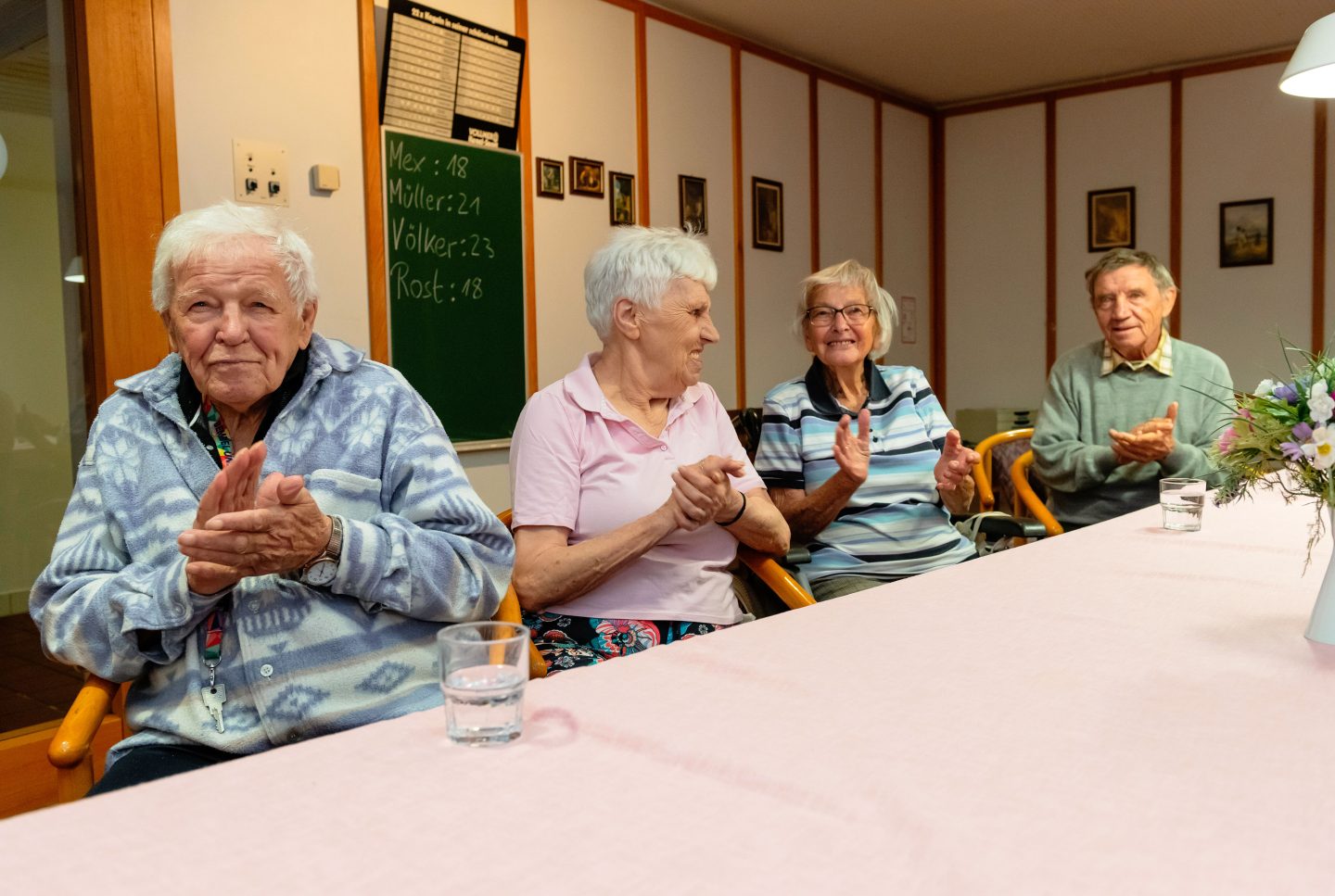 Vier Senioren klatschen und freuen sich zusammen am Esstisch